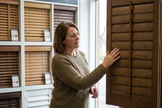 Femme examinant des volets en bois dans un magasin de bricolage